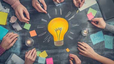Business hands around a drawn lightbulb symbolizing ideas and teamwork